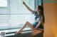 A woman in a school uniform sitting on a window sill.