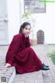 A woman in a red dress sitting on a brick walkway.