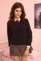 A young woman in a school uniform posing on a bed.