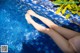 A woman's legs in a swimming pool with her feet in the water.