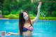 A woman in a bikini splashing water in a pool.