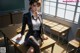 A woman sitting at a desk in a classroom.