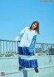 A woman in a white shirt and blue pleated skirt posing for a picture.