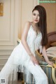 A woman in a white dress sitting on a chair.