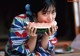 A woman in a kimono eating a slice of watermelon.