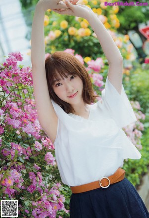 A woman in a white blouse and blue skirt posing for a picture.