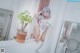 A woman sitting on top of a white counter next to a plant.