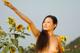 A naked woman standing in a field of sunflowers.