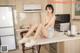 A woman sitting on top of a kitchen counter next to a microwave.